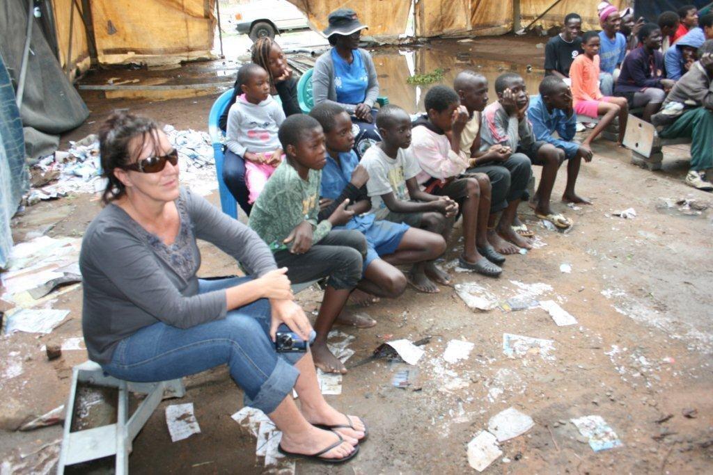ZDDT's Angela Mason and Mazwi Village Head in hat following the proceedings of the drama in a soaked tent